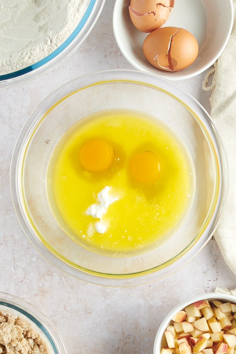 overhead view of butter, sour cream, milk, and eggs in a glass mixing bowl