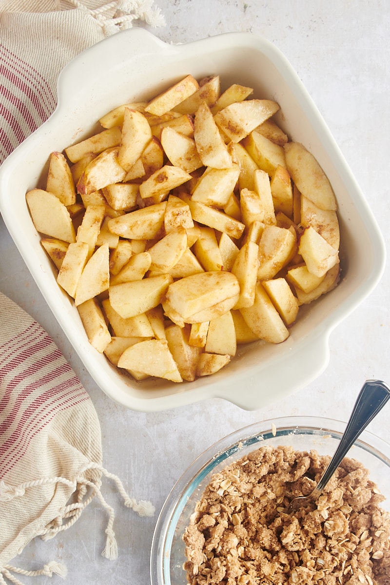 A pan of apple filling next to a bowl of streusel topping.
