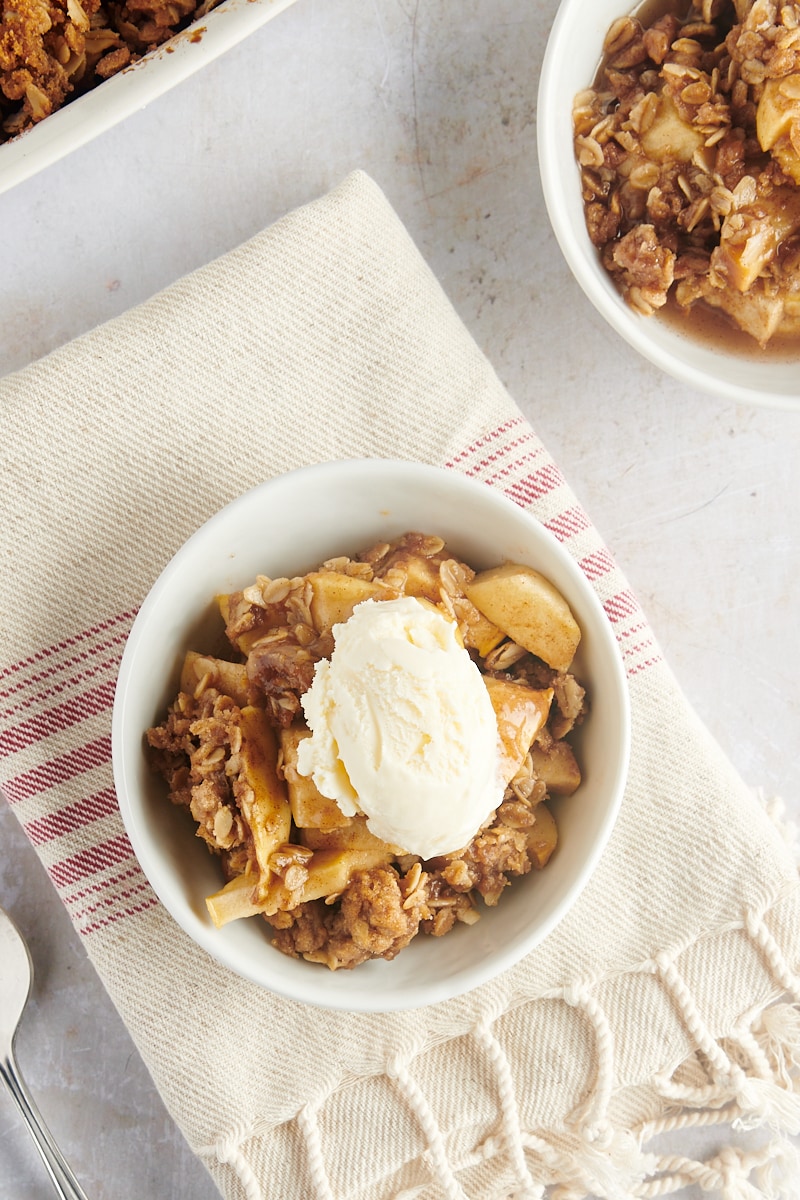 A bowl of apple crisp with a single scoop of vanilla ice cream on top.