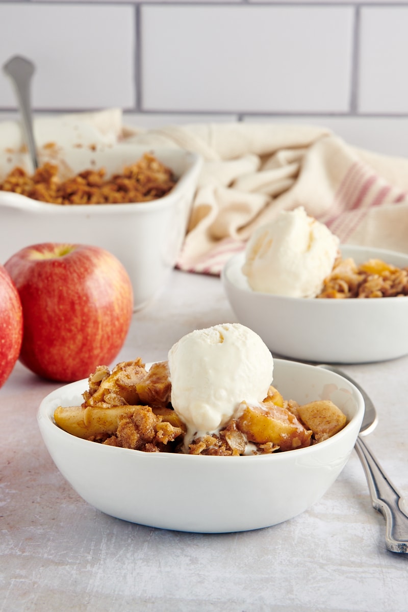 A side-view of a single bowl of apple crisp with ice cream.