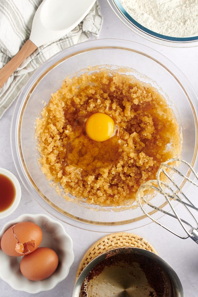 An egg being added to the wet ingredients for chocolate chip cookies.