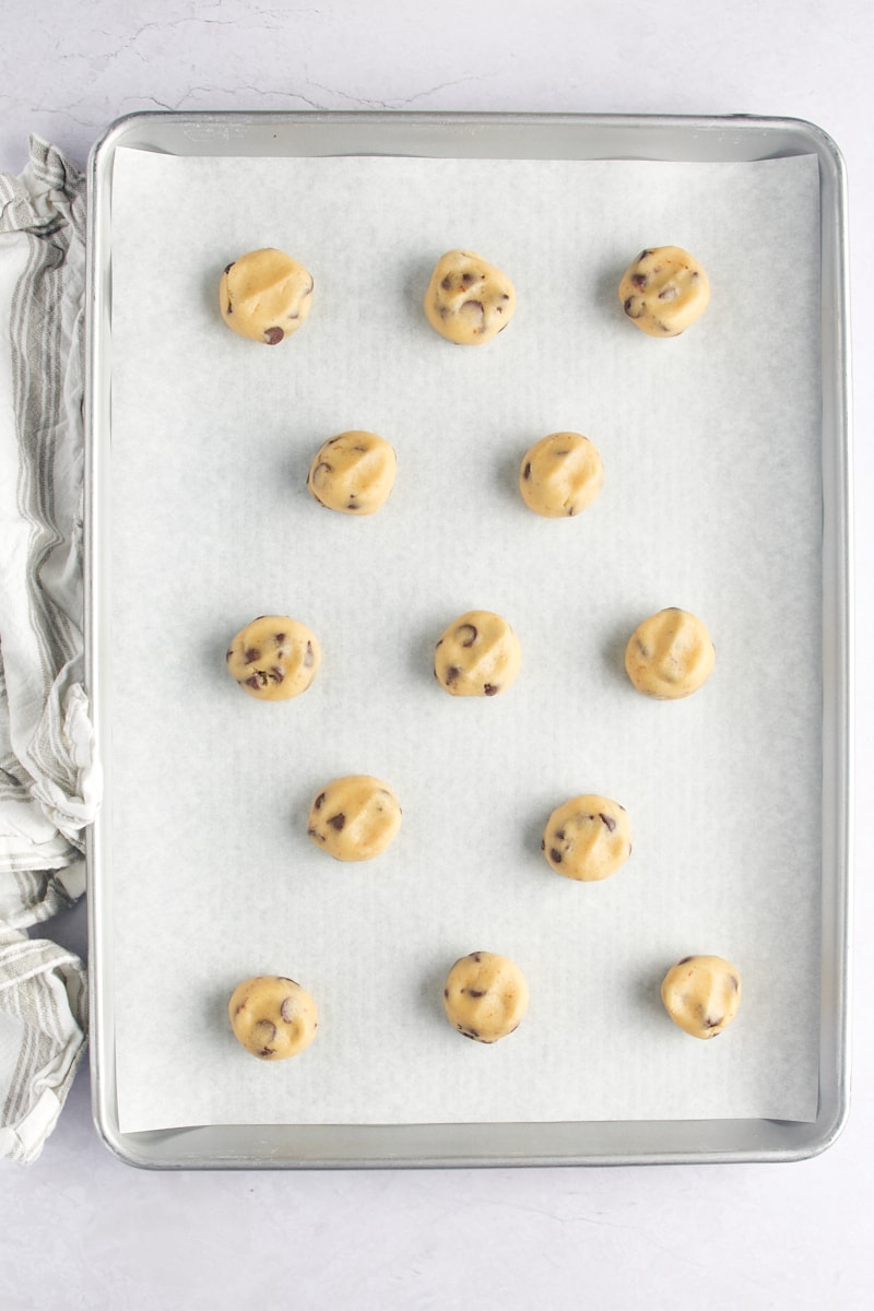 Slightly flattened balls of chocolate chip cookie dough on a baking sheet.
