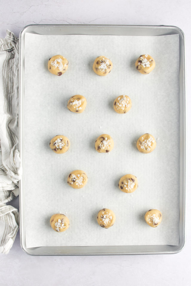 Salt sprinkled on top of balls of chocolate chip cookie dough.