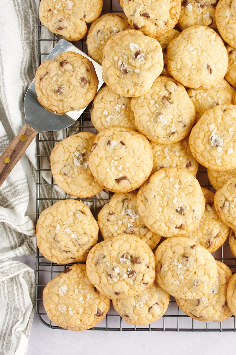 Chocolate chip cookies piled on a cooling rack.