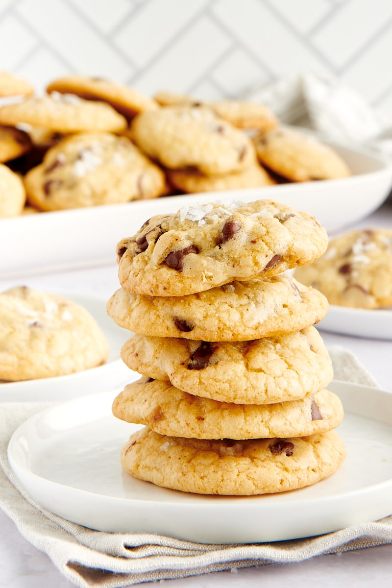 Five chocolate chip cookies stacked on a plate.