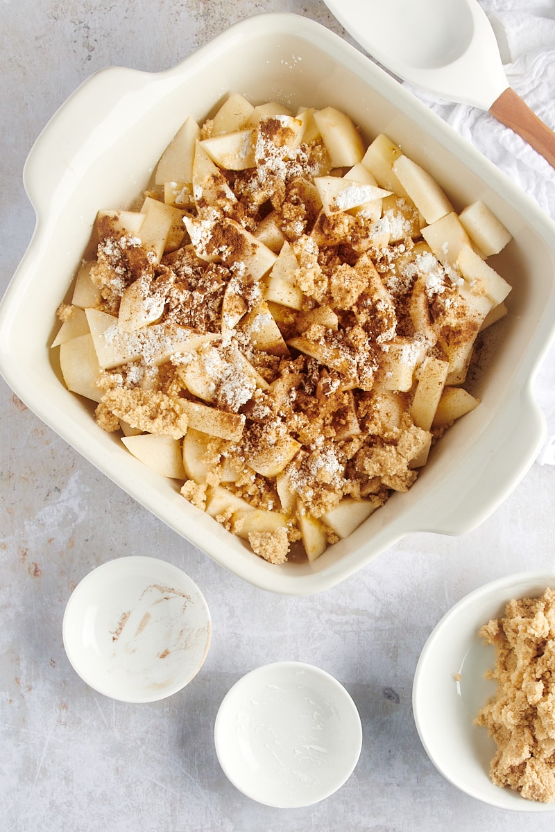 overhead view of sliced pears, brown sugar, cornstarch, and cinnamon in a white baking dish