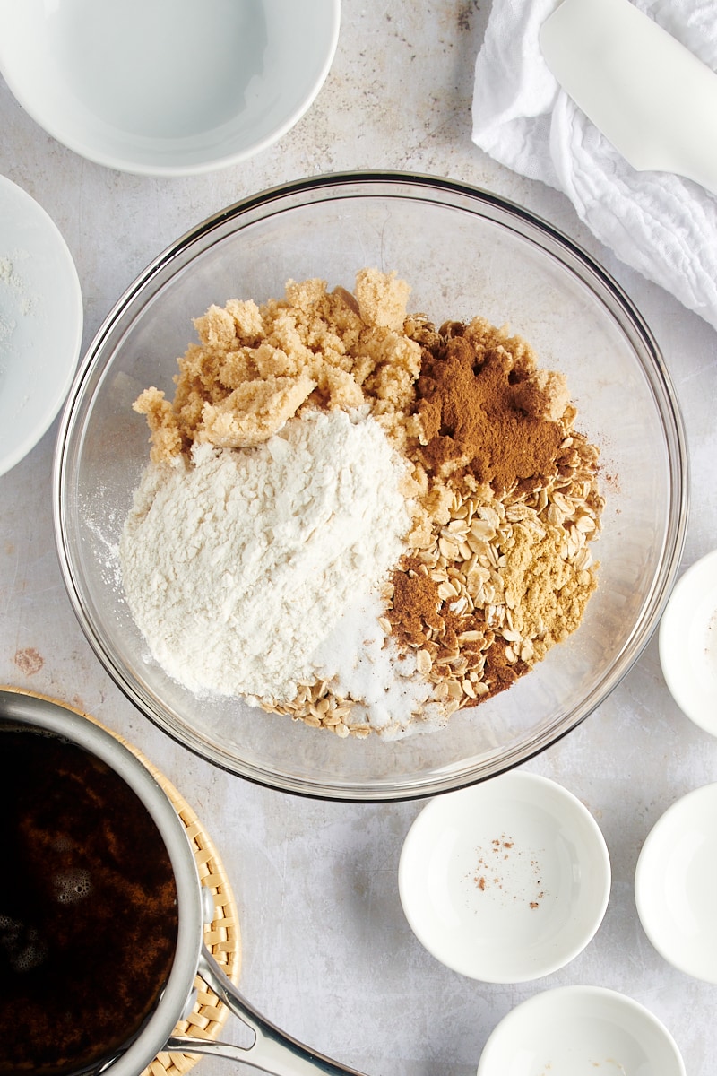 overhead view of oats, brown sugar, flour, and spices in a glass mixing bowl