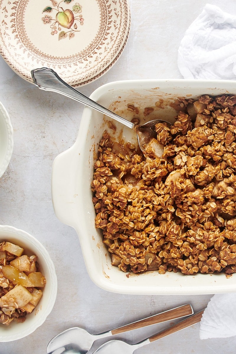 overhead view of Brown Butter Pear Crisp in a white baking dish with a serving spoon
