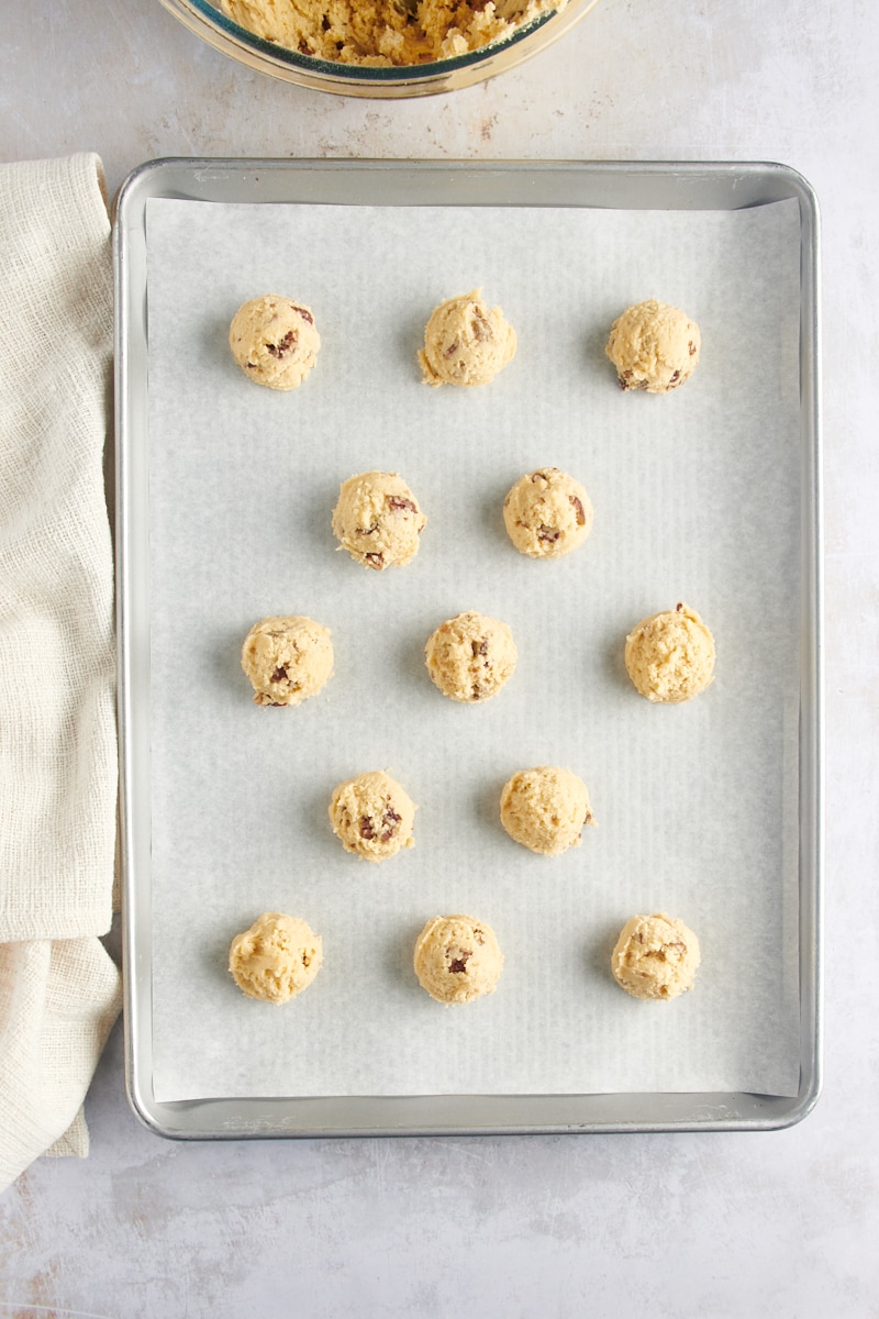 overhead view of scooped Maple Pecan Cookie dough on a parchment-lined baking sheet