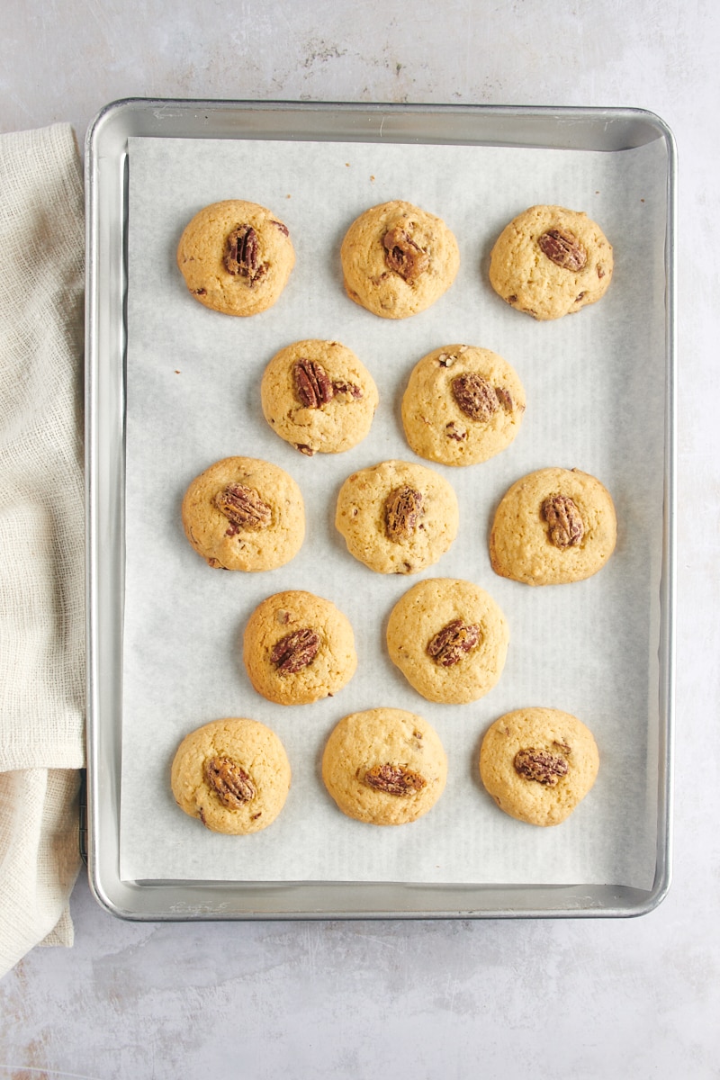 overhead view of freshly baked Maple Pecan Cookies on a parchment-lined baking sheet