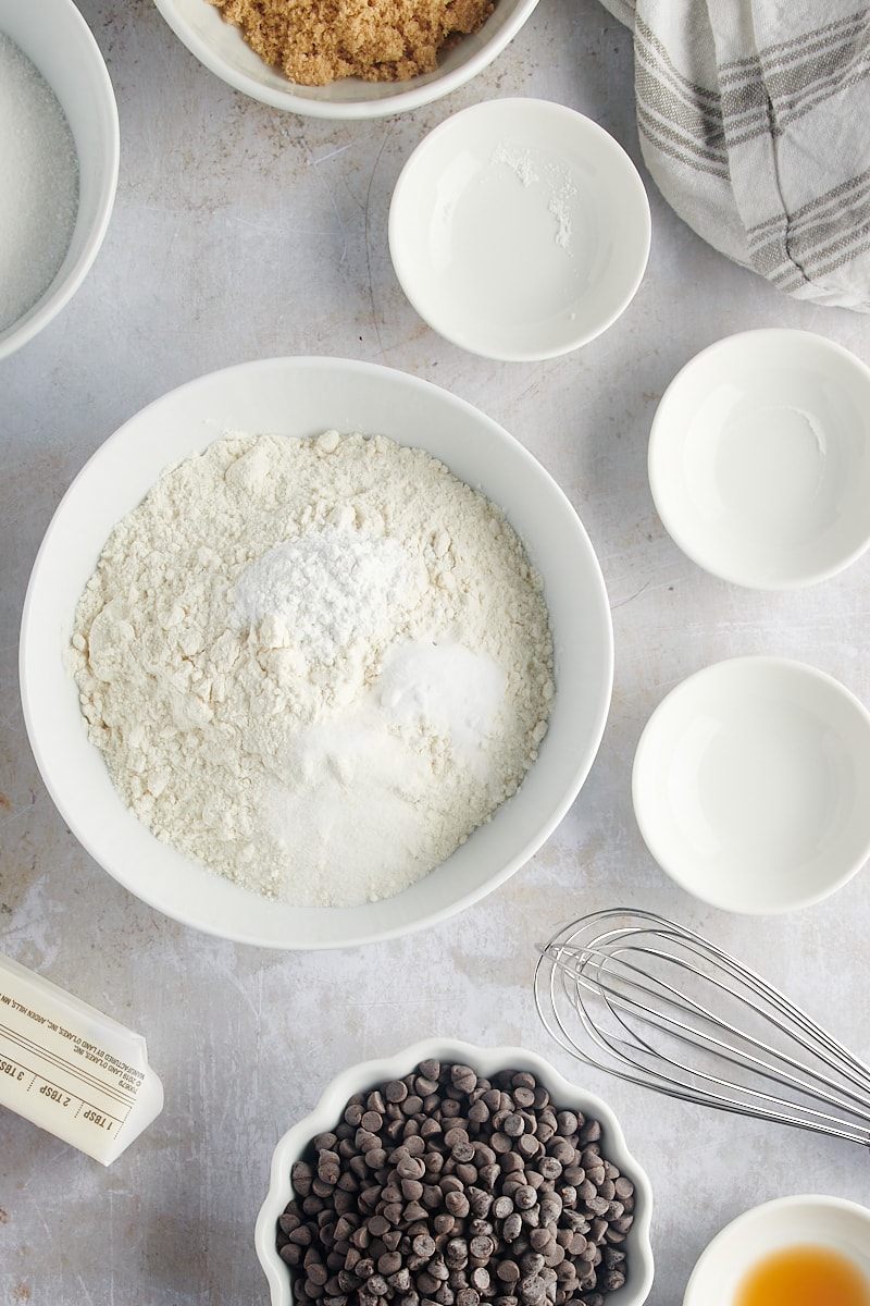 overhead view of flour, baking powder, baking soda, and salt in a white mixing bowl