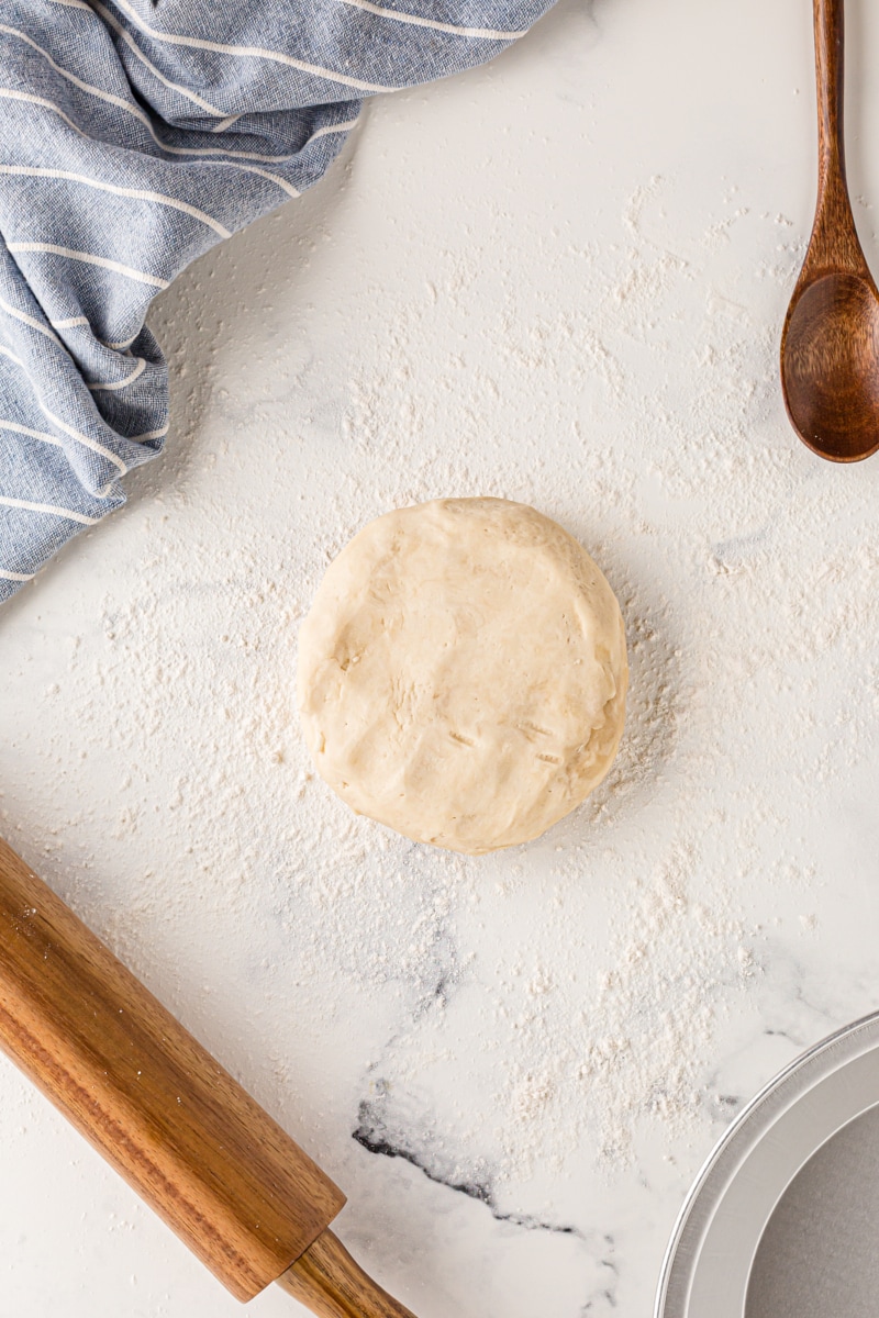 overhead view of a disc of pie crust dough on a floured surface