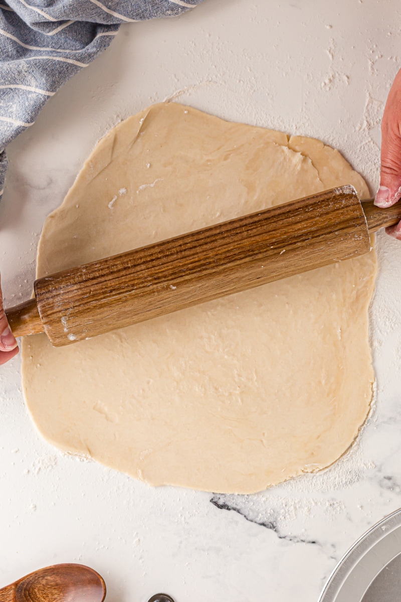 overhead view of pie crust being rolled out with a wooden rolling pin
