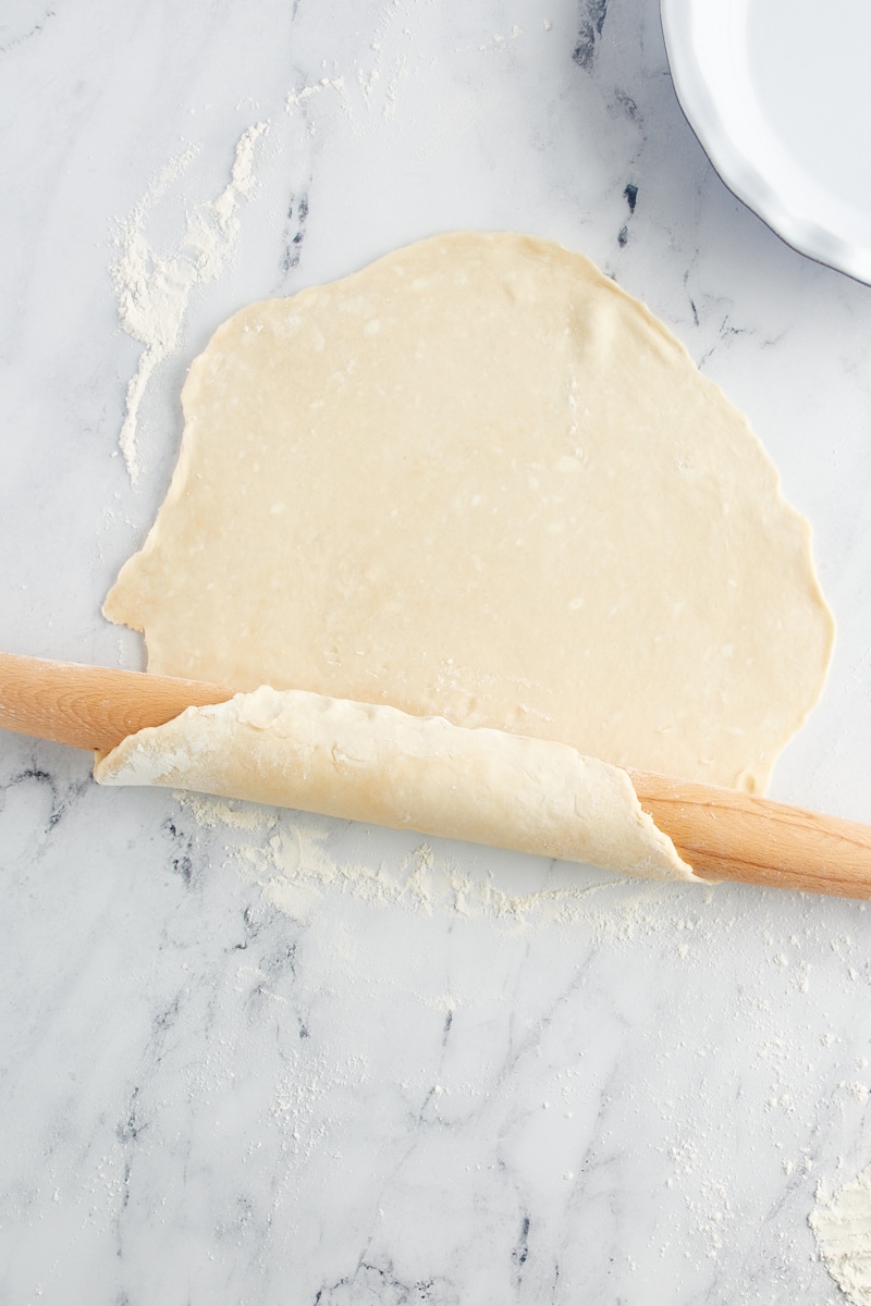 overhead view of pie crust beginning to wrap around a rolling pin