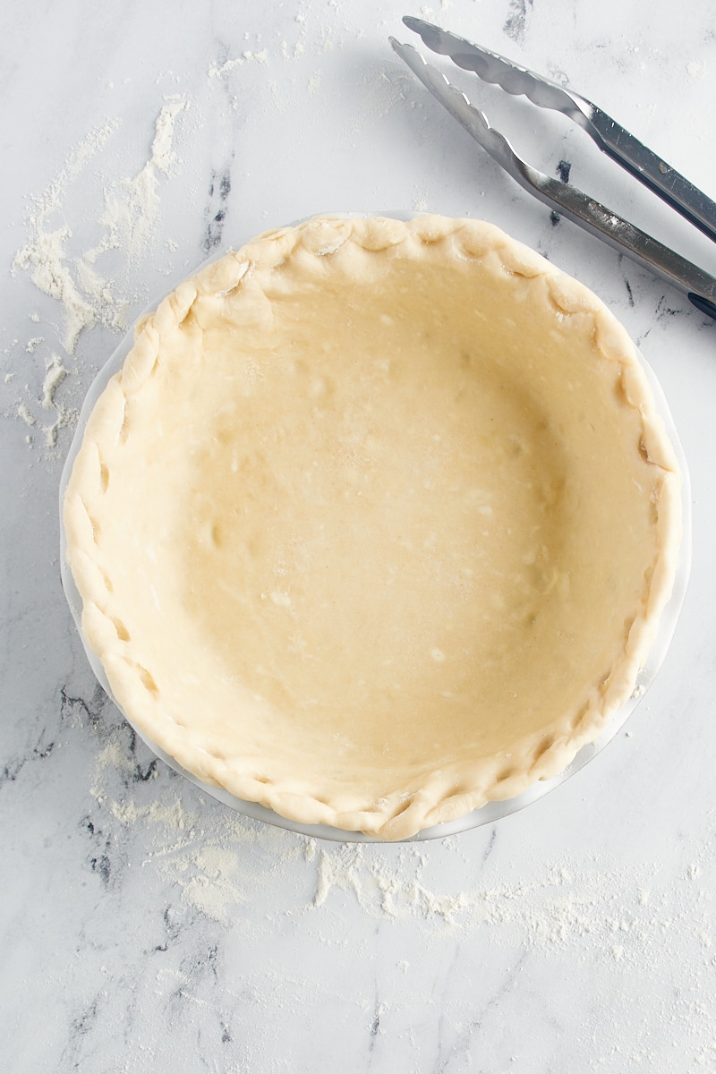 overhead view of a decorative pie crust edge made with kitchen tongs