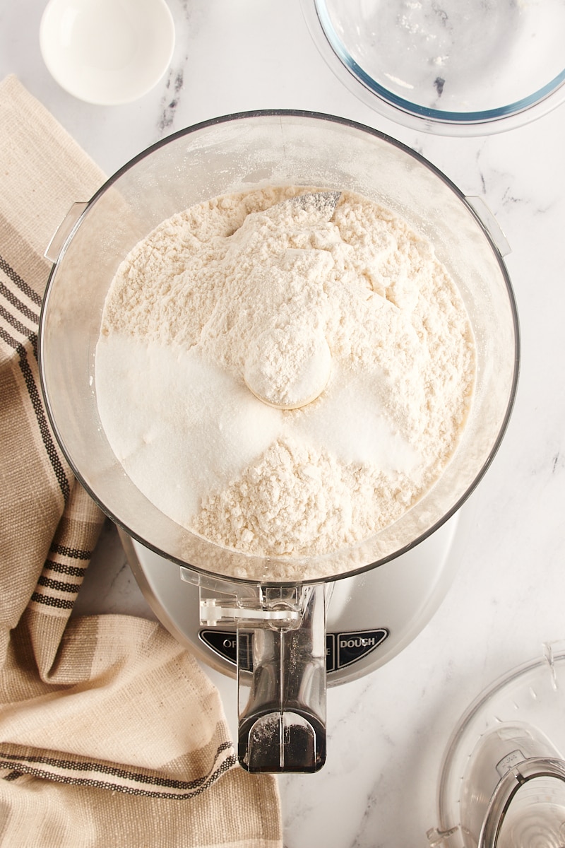 overhead view of flour, sugar, and salt in the bowl of a food processor