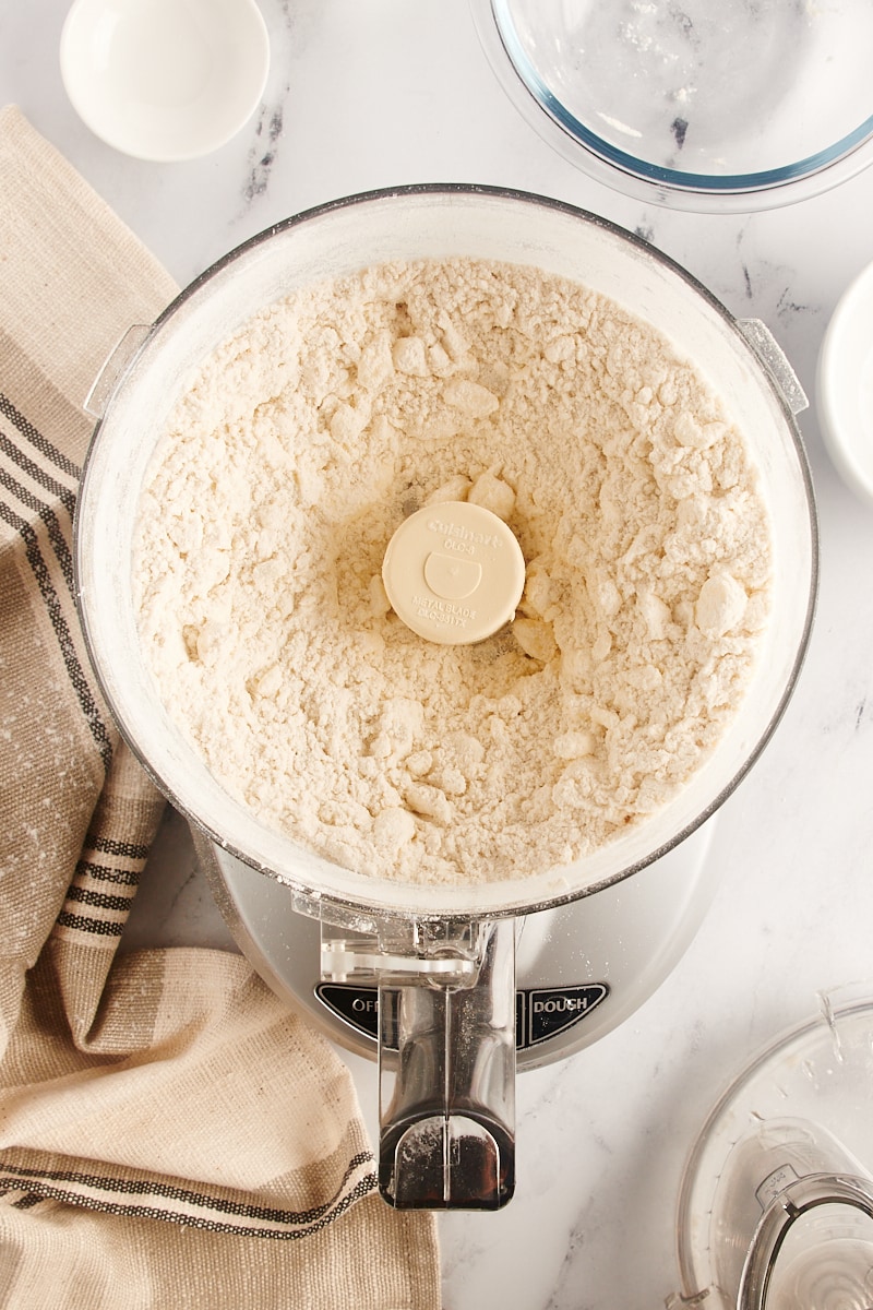 overhead view of partially mixed pie crust dough in a food processor