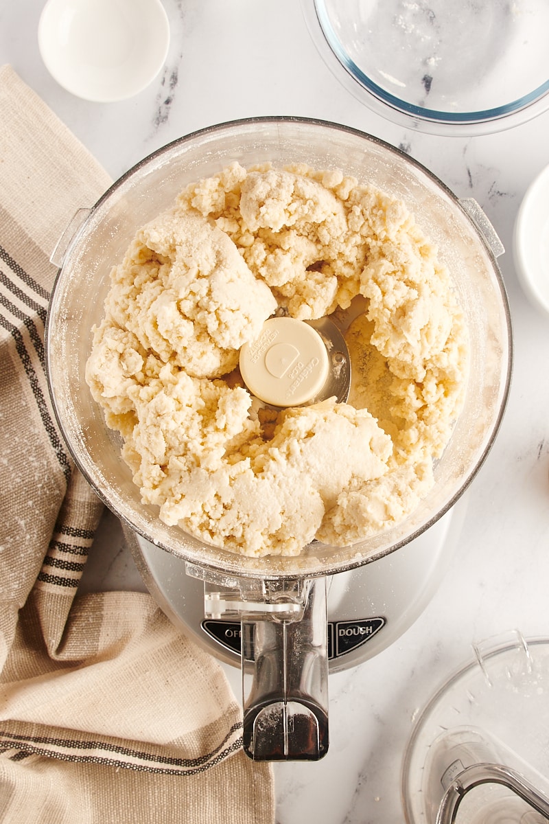 overhead view of pie crust dough in the bowl of a food processor