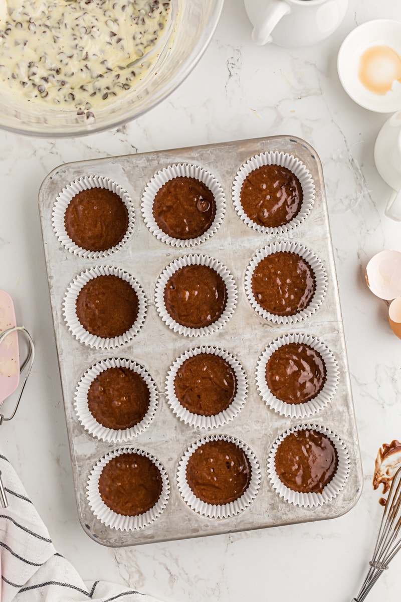 Muffin cups filled 1/3 of the way with chocolate batter.