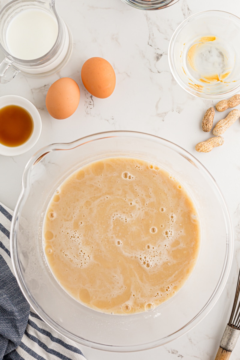 combining wet ingredients for the cake in a glass mixing bowl