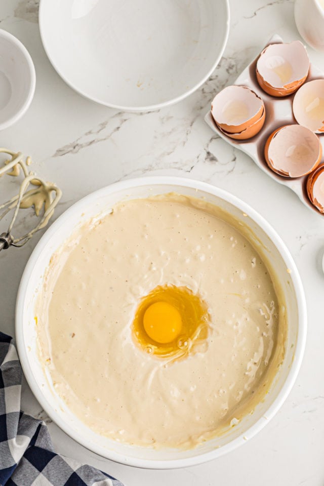 Adding eggs to cheesecake batter.