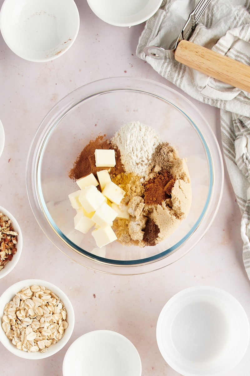 overhead view of butter, flour, and spices in a glass mixing bowl