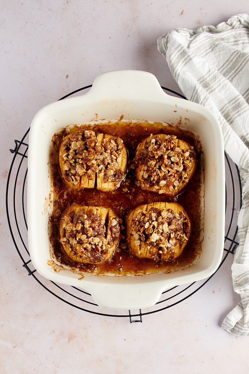 overhead view of baked hasselback apples in a white baking dish on a wire cooling rack