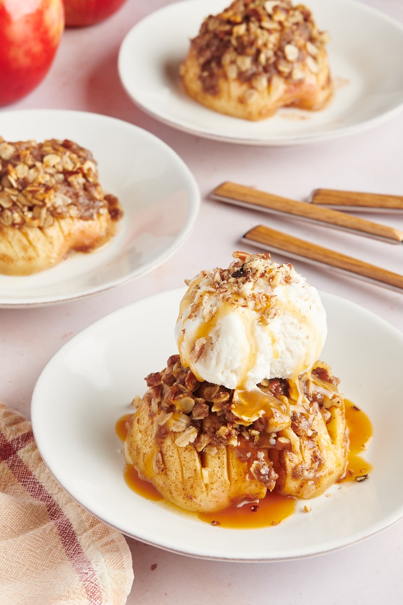 three servings of baked hasselback apples on white plates