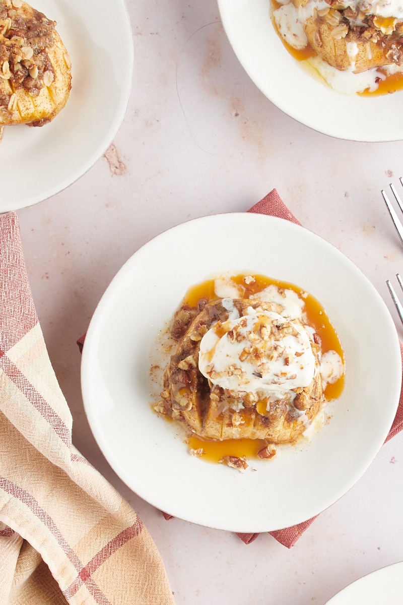 overhead view of a baked hasselback apple topped with ice cream, caramel sauce, and nuts