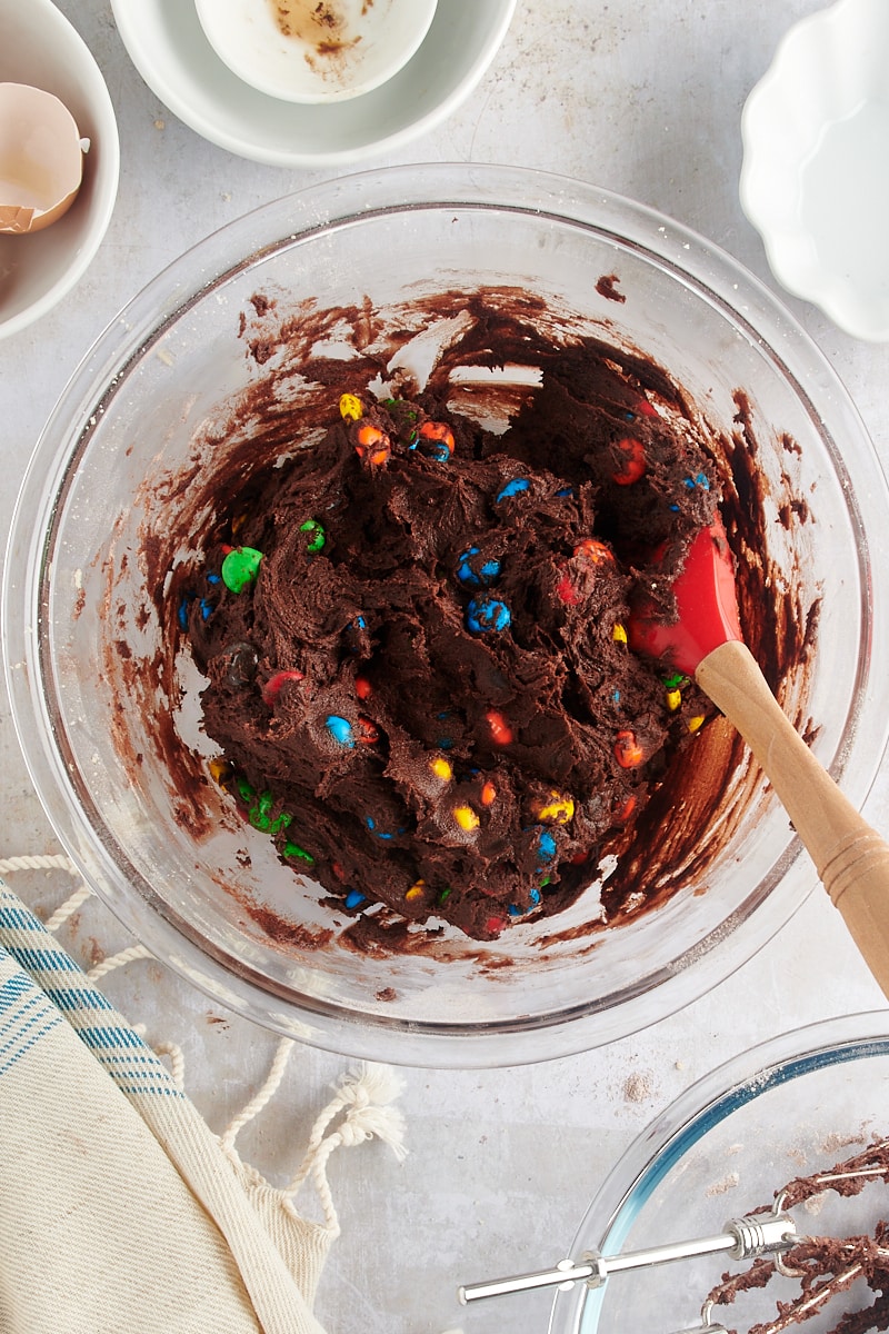 overhead view of mixed Chocolate M&M Cookie dough in a glass mixing bowl