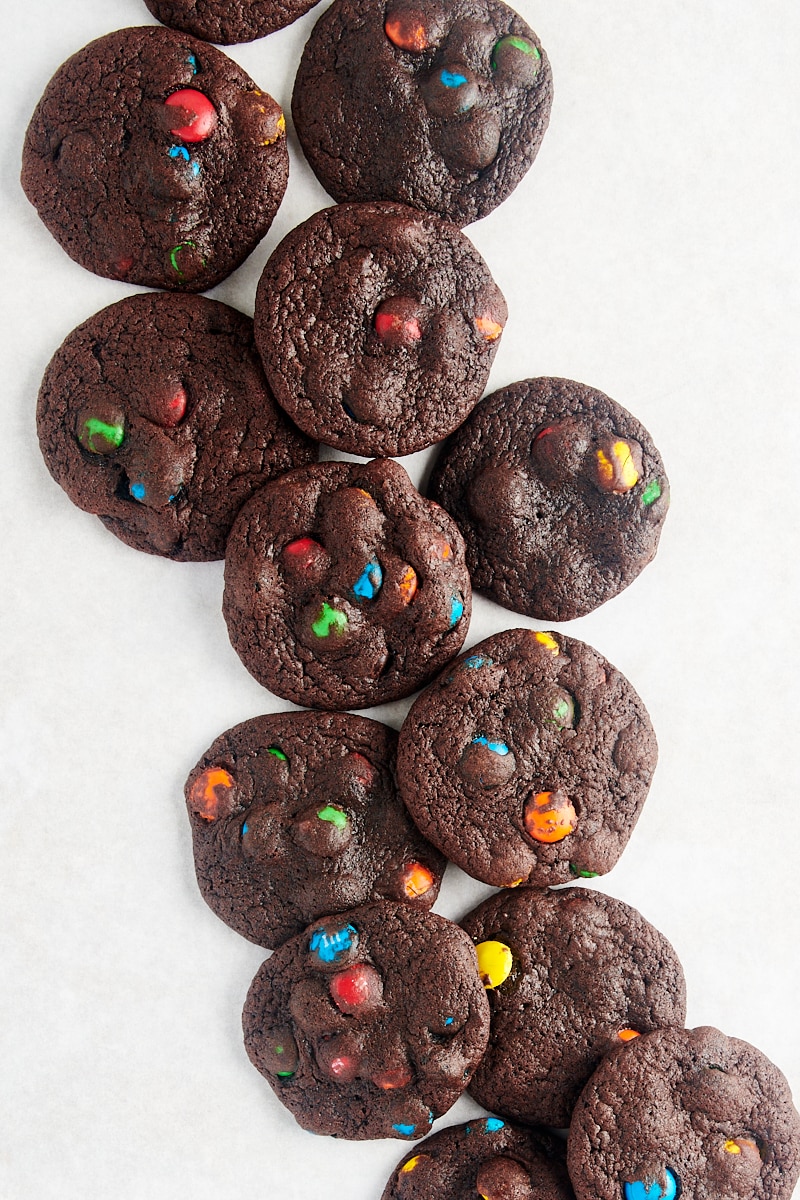 overhead view of Chocolate M&M Cookies scattered over a white surface