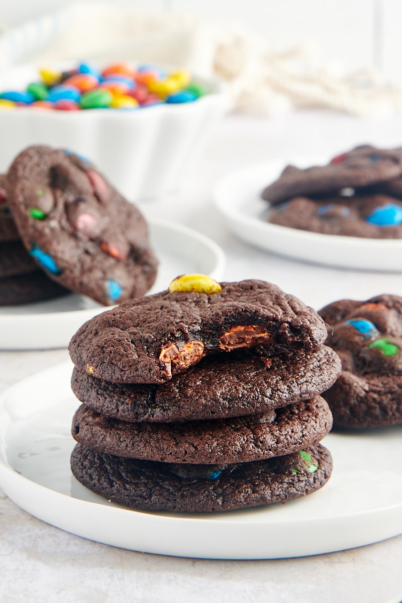 stack of four Chocolate M&M Cookies with a bite taken out of the top cookie