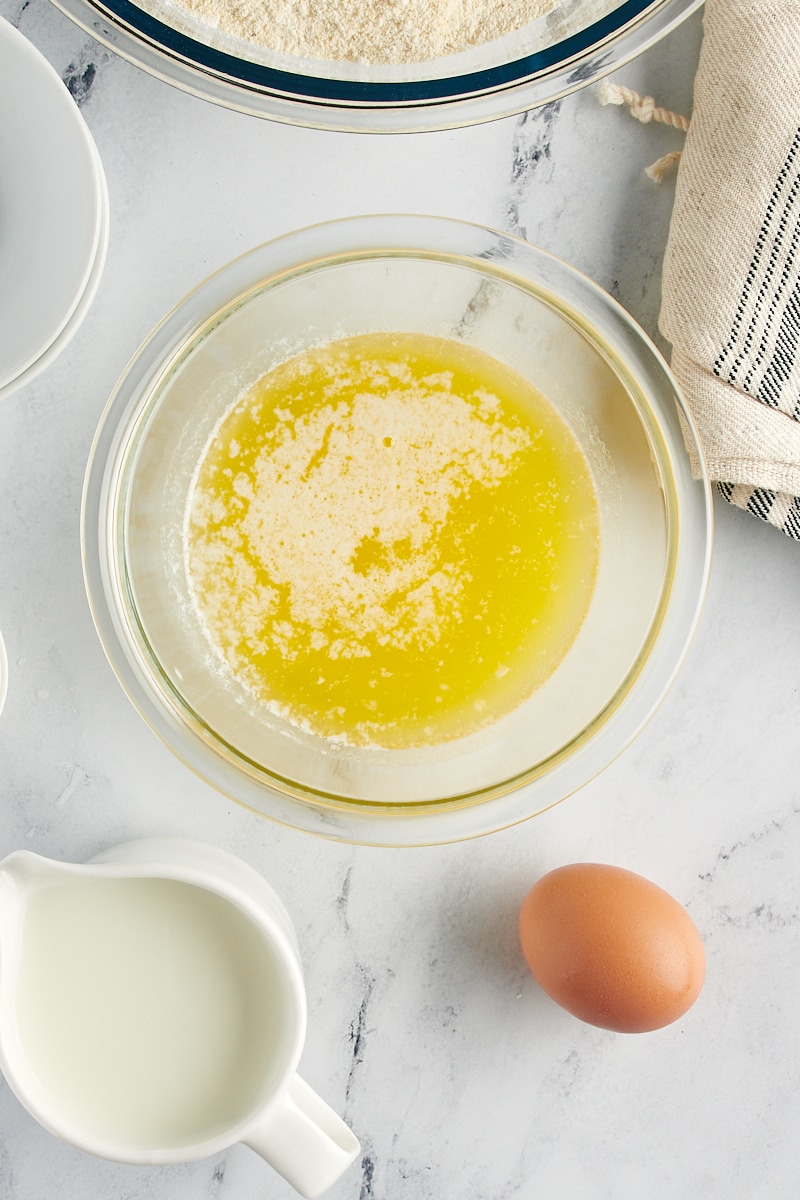 Melted butter in a glass bowl near an egg.