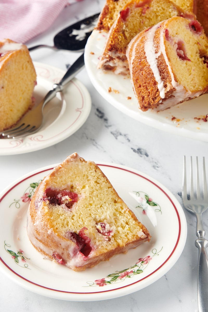 A slice of cranberry bundt cake on a plate with more slices in the background.