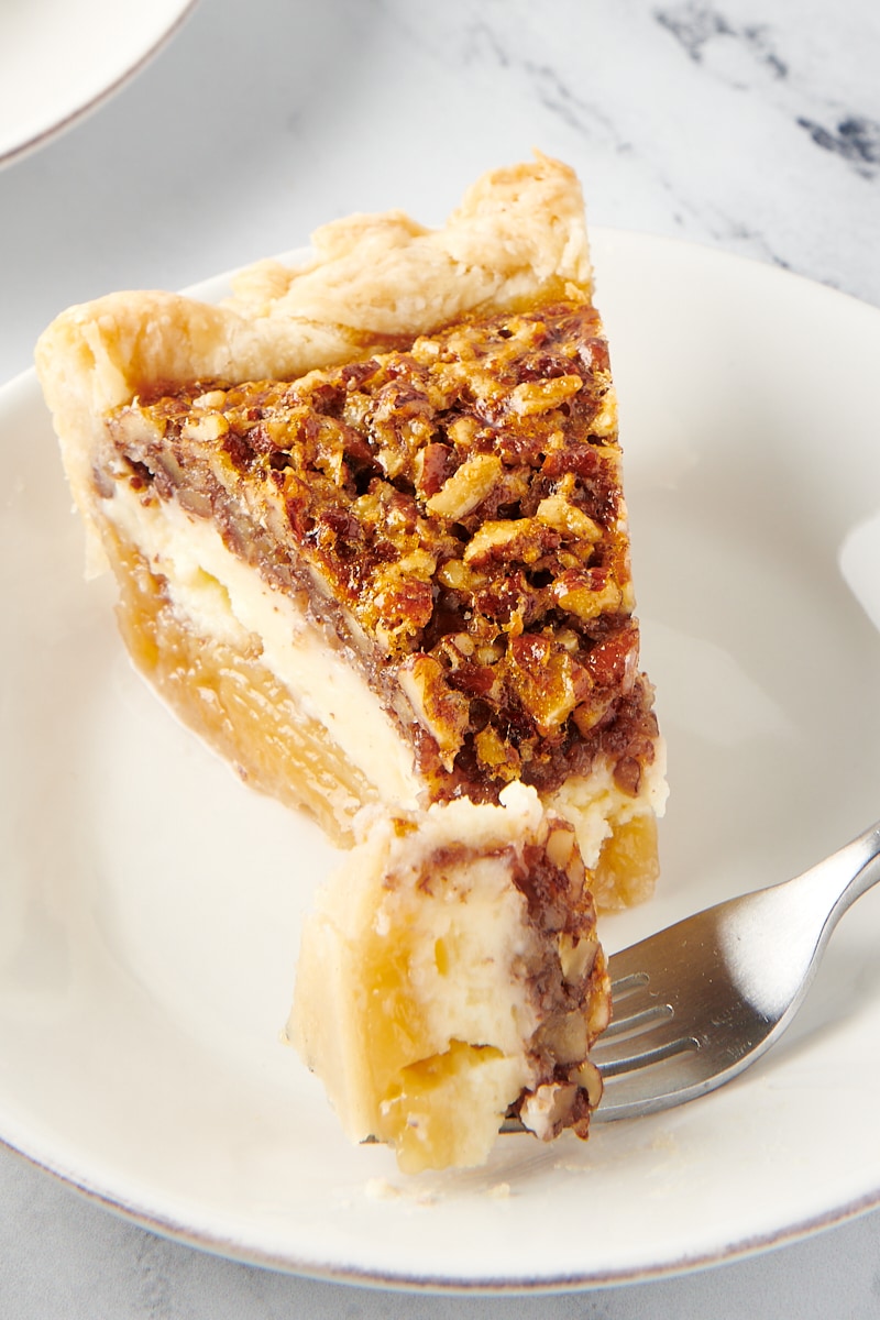 slice of Pecan Cheesecake Pie with a bite on a fork