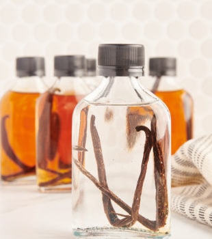 a freshly made bottle of vanilla extract in front of several bottles of aged vanilla extract