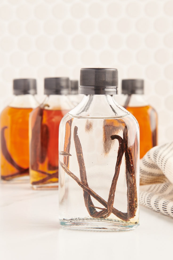a freshly made bottle of vanilla extract in front of several bottles of aged vanilla extract