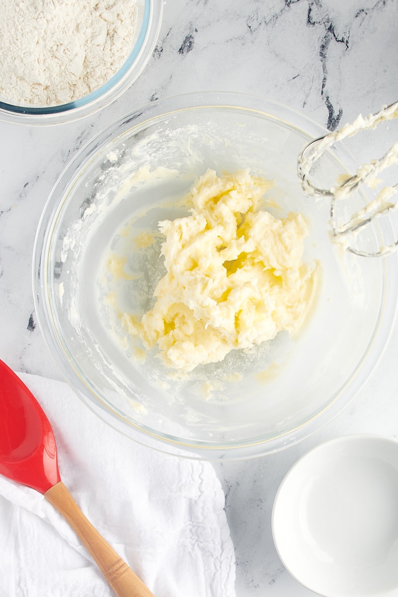 Overhead view of creamed butter and confectioners' sugar in a glass mixing bowl.
