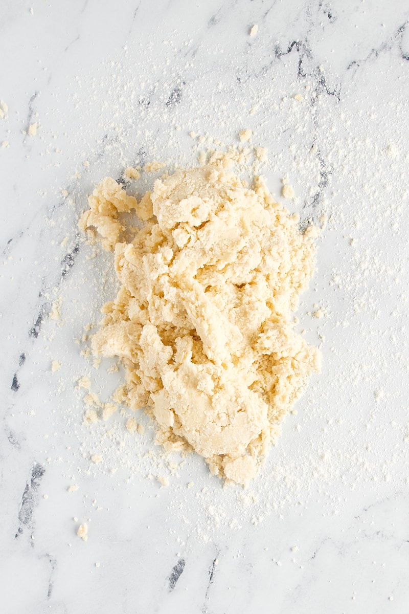 Overhead view of shortbread cookie dough on a lightly floured marble surface.