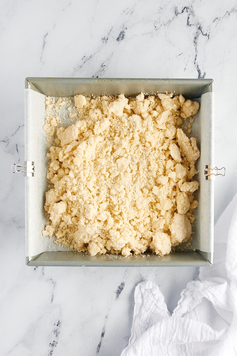Overhead view of shortbread cookie dough in a parchment-lined square baking pan.