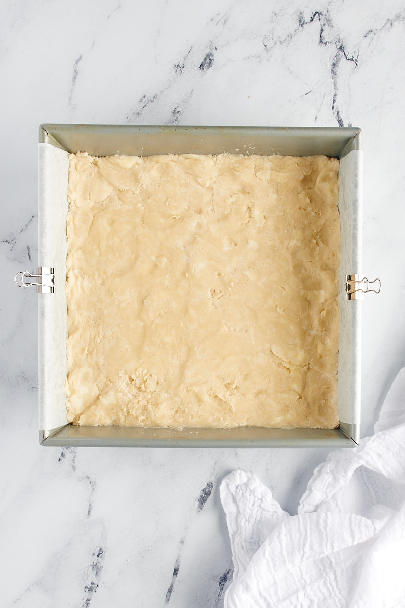 overhead view of shortbread dough pressed into a square baking pan