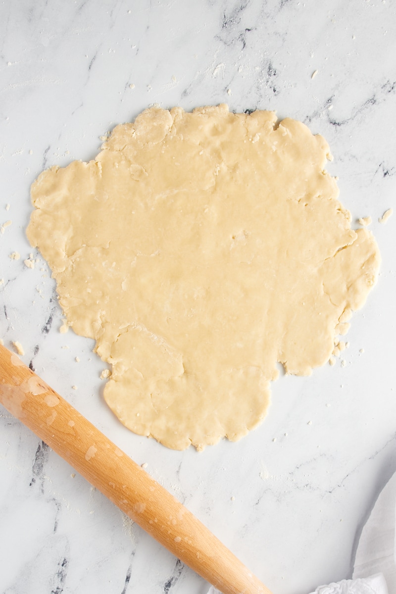 Rolled shortbread cookie dough on a marble surface.