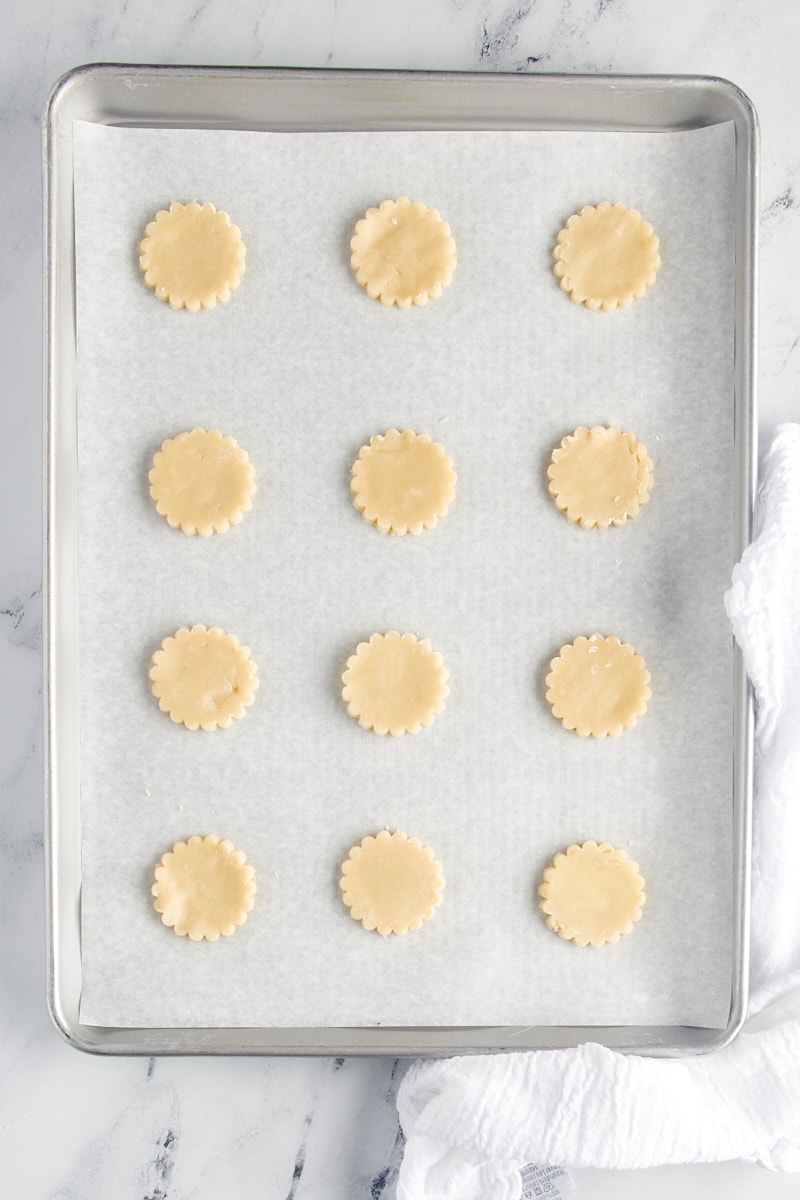 Shortbread cookie cutouts on a parchment-lined baking sheet.