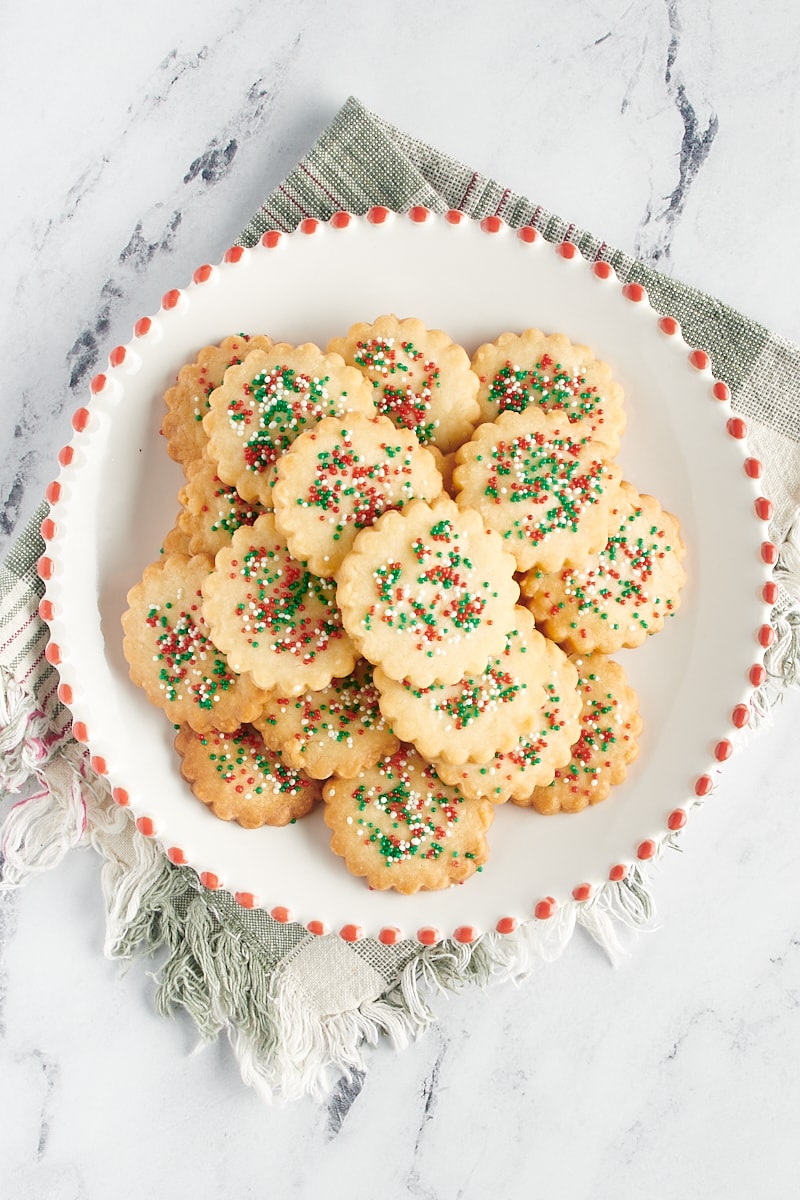 Overhead view of cutout shortbread cookies on a red-rimmed white plate.