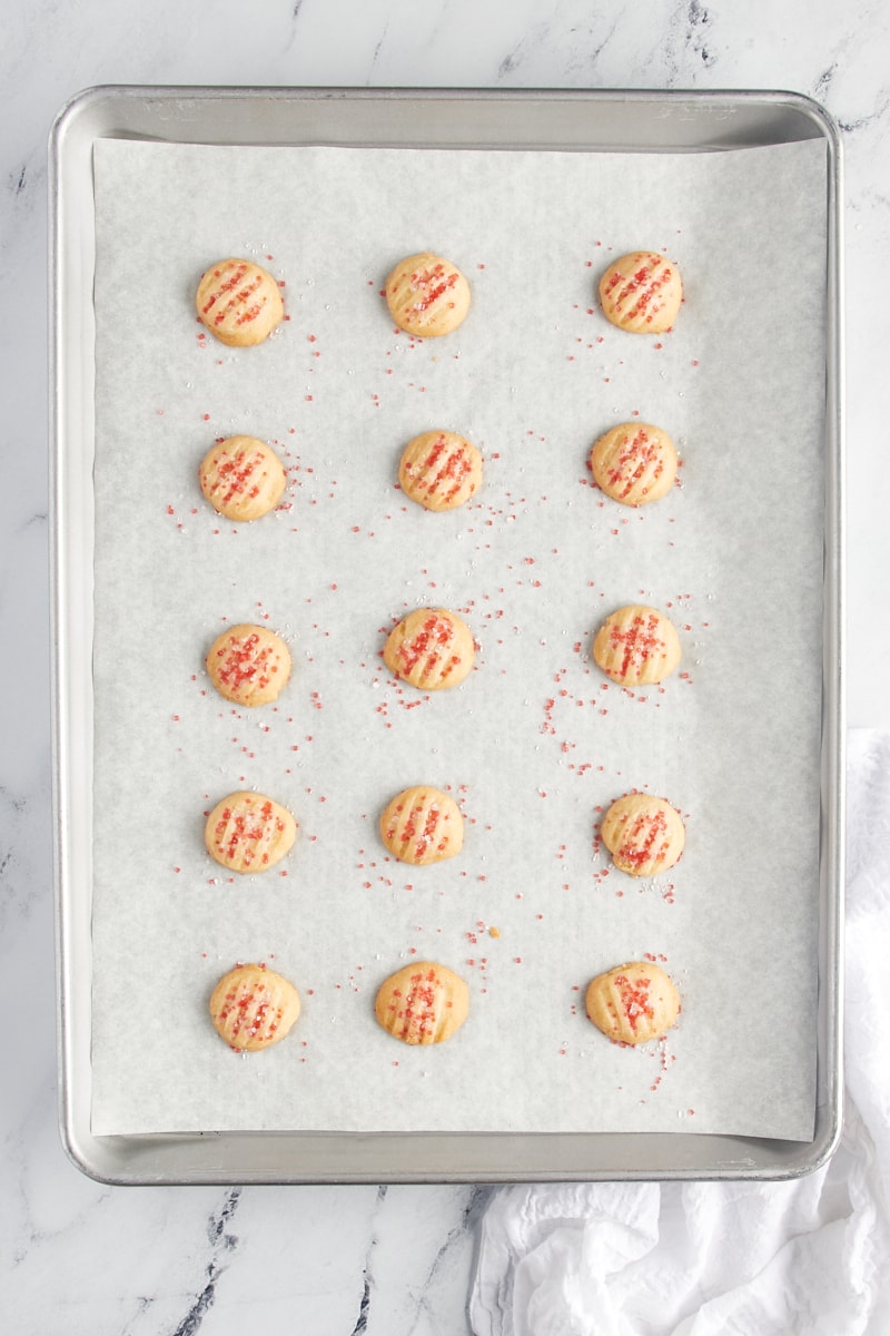 Overhead view of freshly baked drop shortbread cookies on a baking sheet.