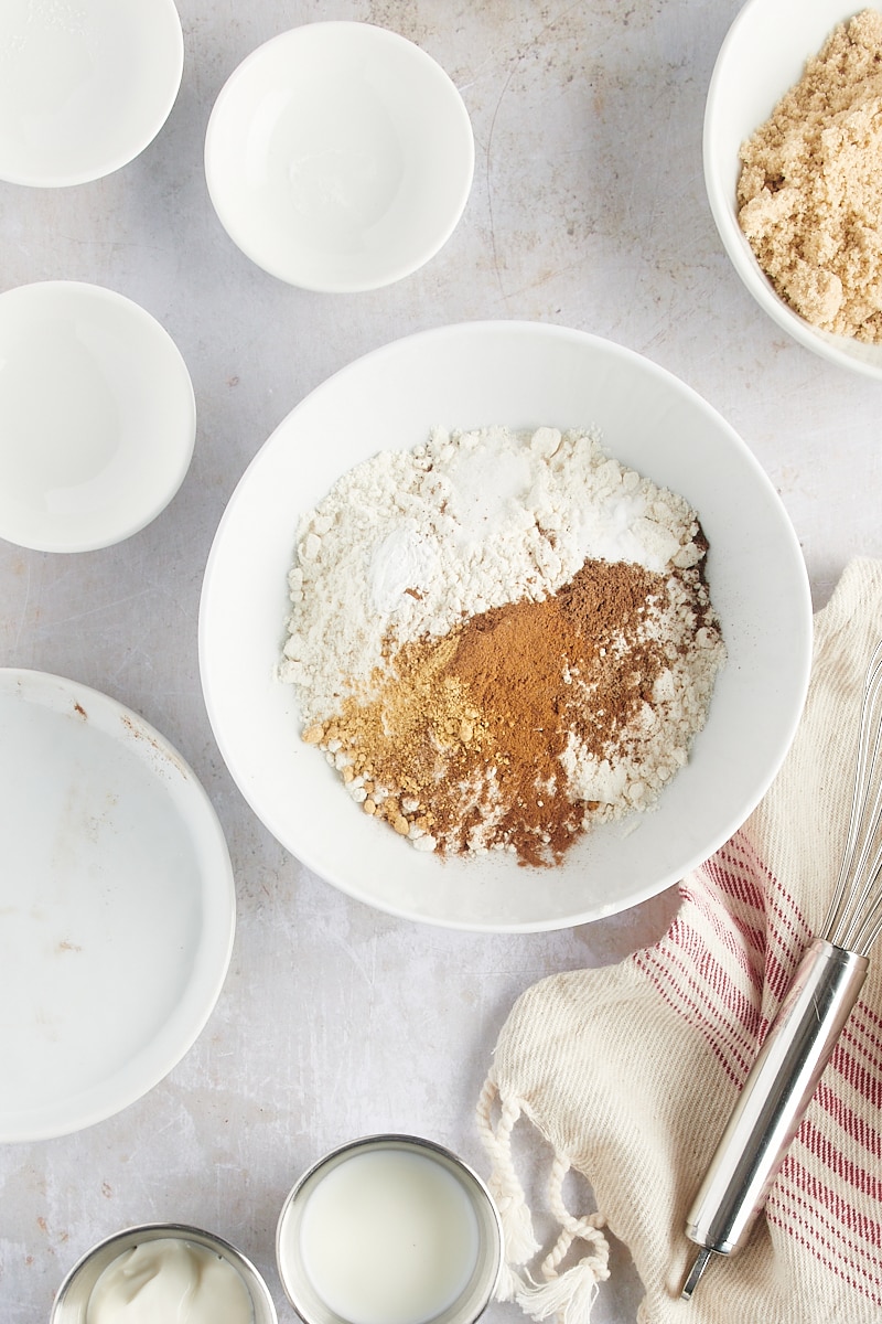 overhead view of flour, baking powder, baking soda, salt, and spices in a white mixing bowl