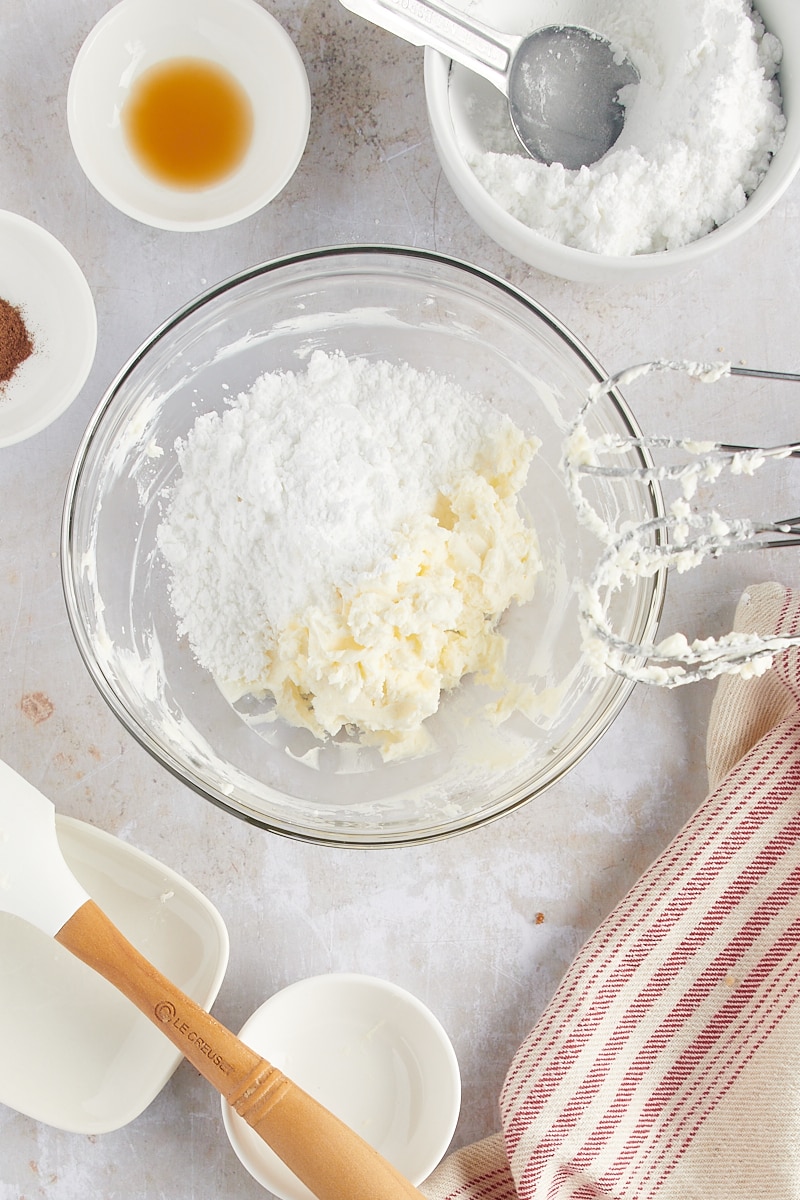 overhead view of confectioners' sugar added to cream cheese frosting