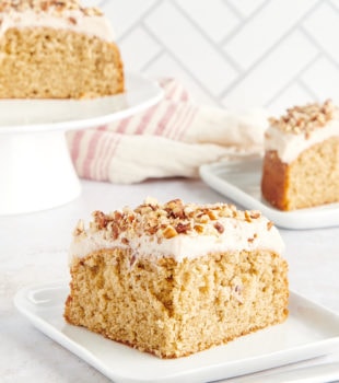 slice of Spice Cake on a white plate with more cake in the background