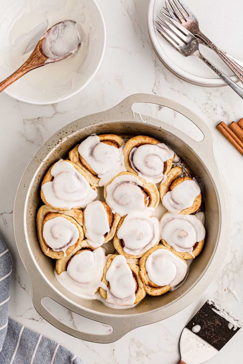 overhead view of iced cinnamon rolls in a round baking pan