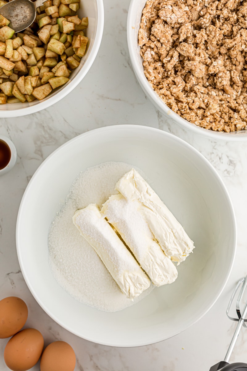 overhead view of cream cheese and sugar in a white mixing bowl